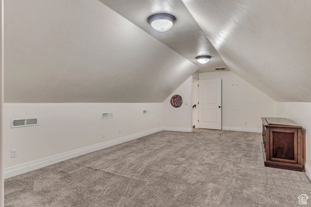 Bonus room featuring carpet floors, lofted ceiling, and baseboards