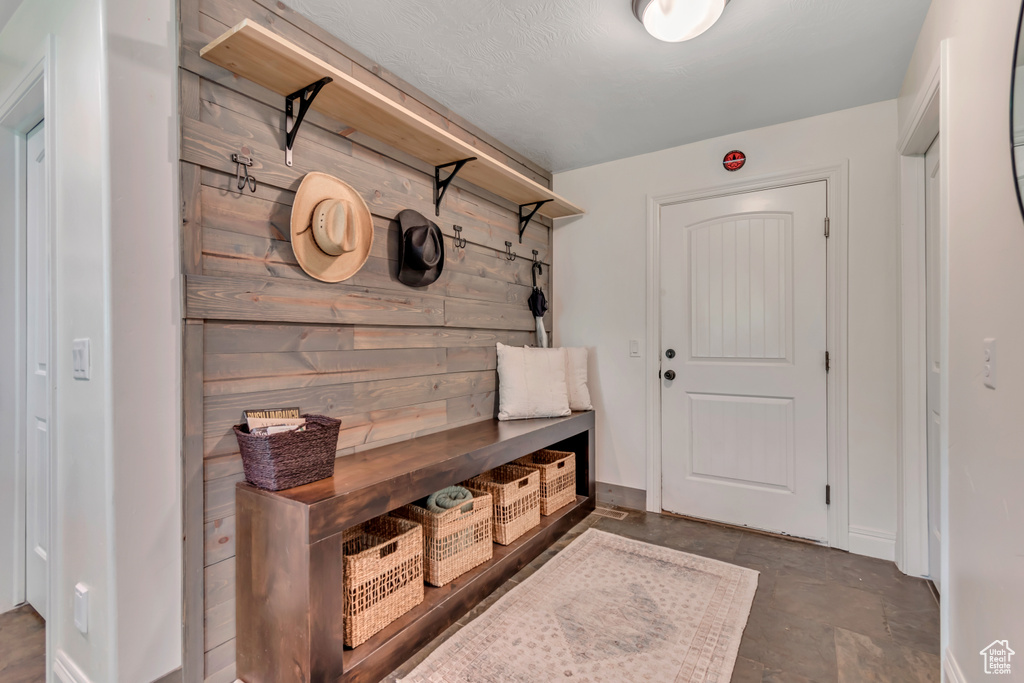 Mudroom featuring concrete flooring and wooden walls
