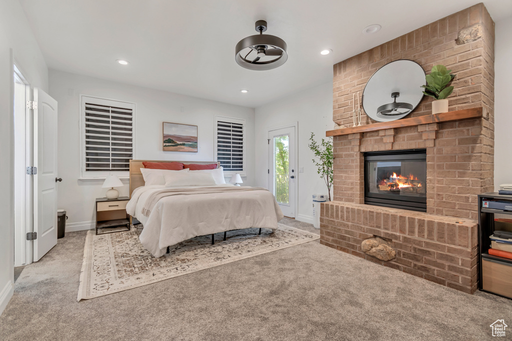Carpeted bedroom featuring a fireplace, baseboards, recessed lighting, and access to outside