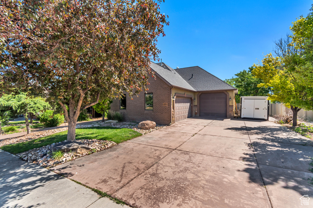 View of front of house with a garage, brick siding, driveway, and a shingled roof