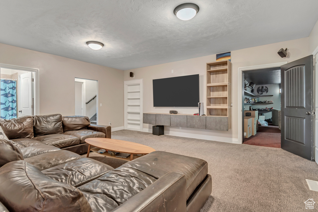 Carpeted living area with a textured ceiling, baseboards, and stairway