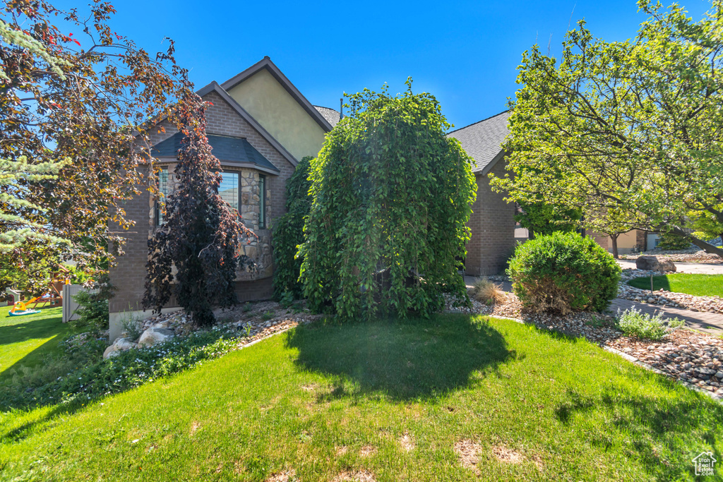 View of side of property with a lawn, brick siding, and stucco siding