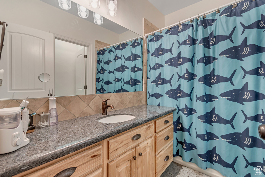 Bathroom featuring vanity, backsplash, and a shower with shower curtain