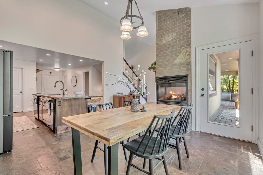Dining room featuring a fireplace, stairs, a high ceiling, and stone finish flooring
