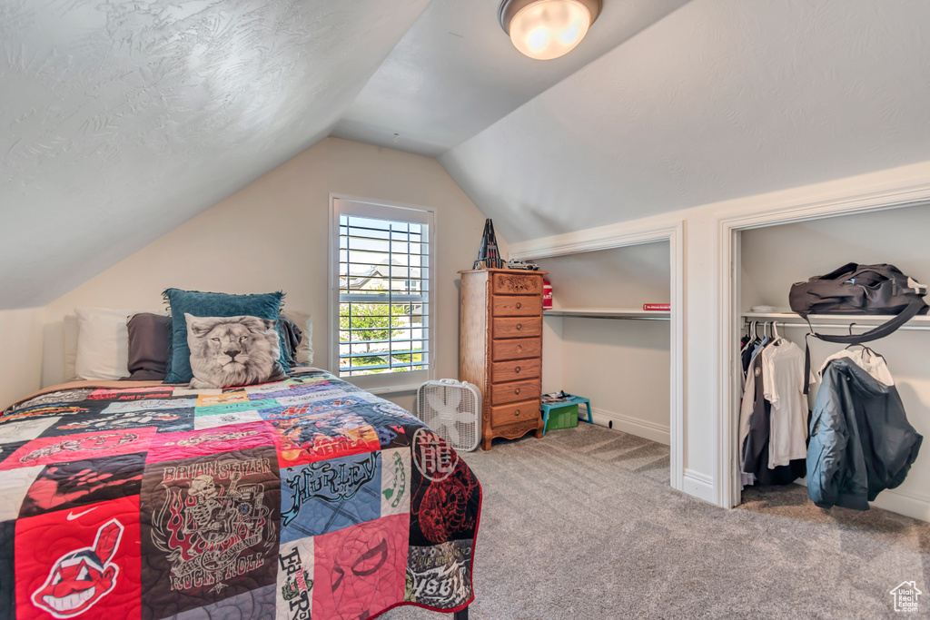 Bedroom featuring carpet, lofted ceiling, and baseboards