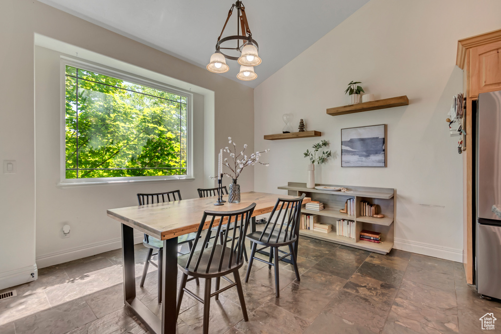 Dining area featuring baseboards, stone tile floors, and vaulted ceiling