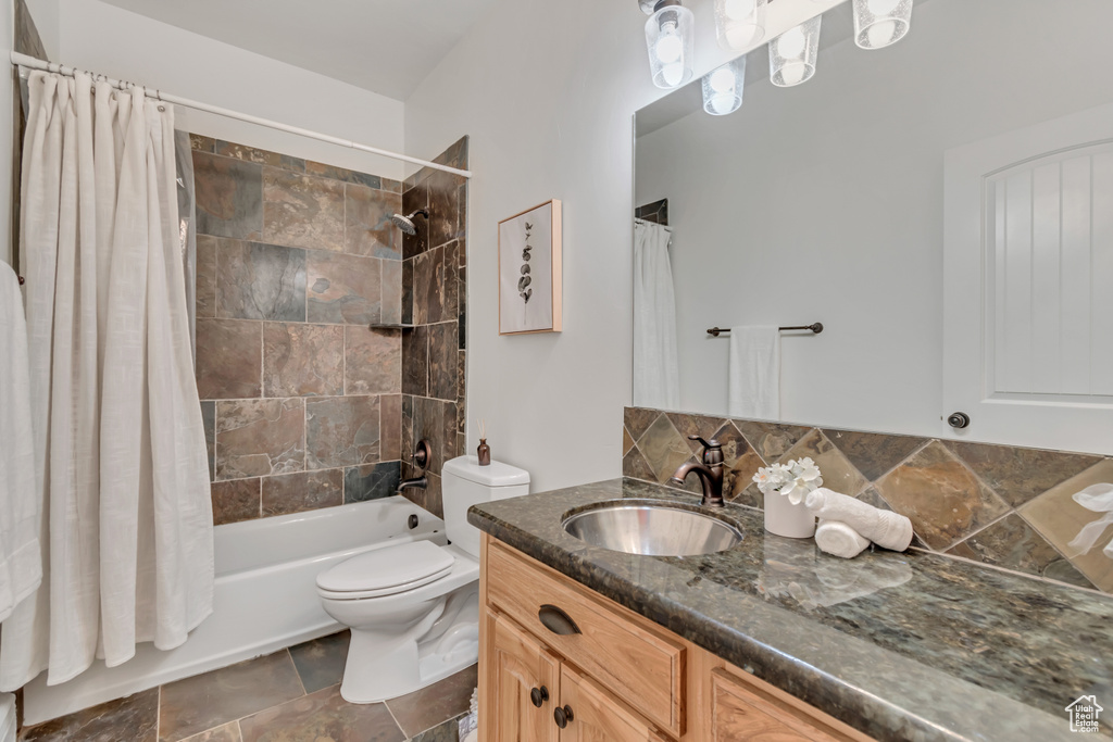 Full bathroom featuring vanity, toilet, shower / bathtub combination with curtain, and tasteful backsplash