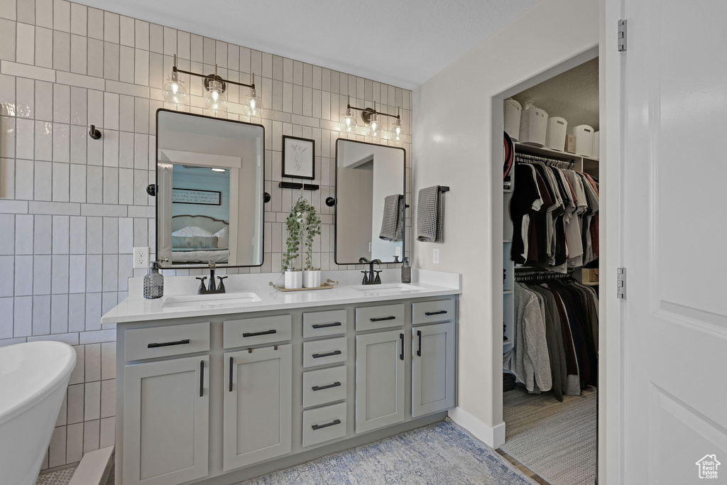 Bathroom featuring tile walls, double vanity, a walk in closet, and a freestanding bath