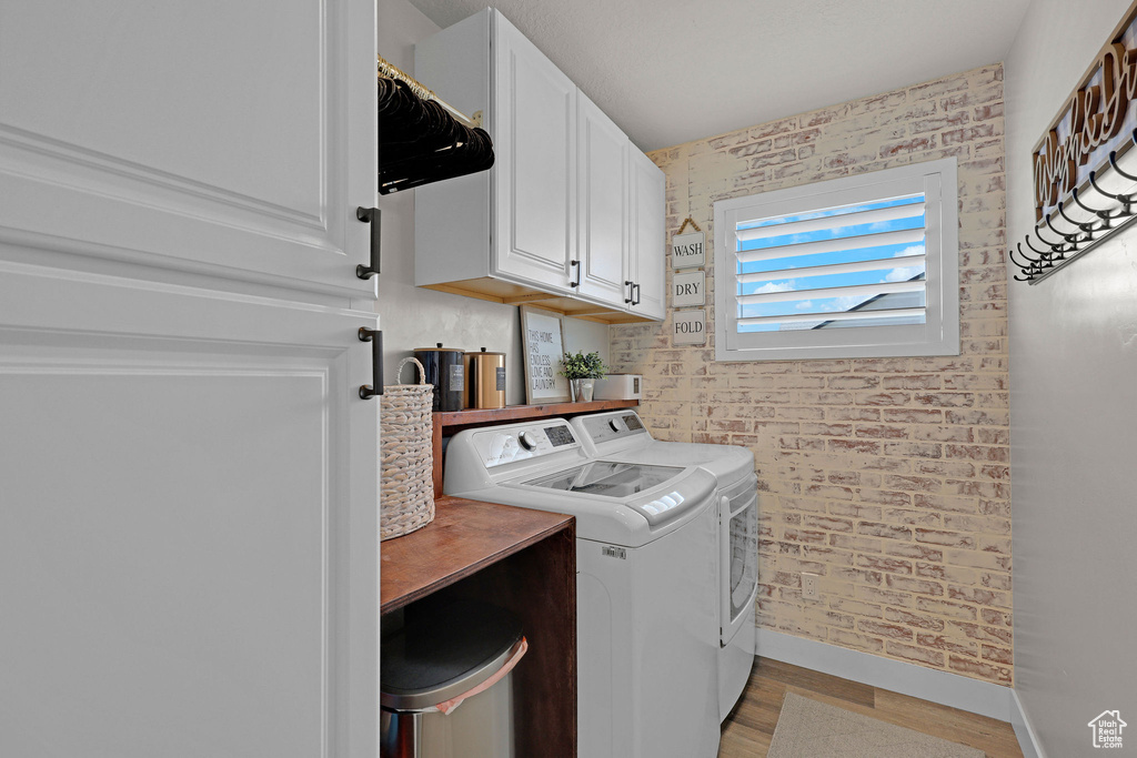 Laundry room with washer and dryer, cabinet space, baseboards, and light wood-type flooring