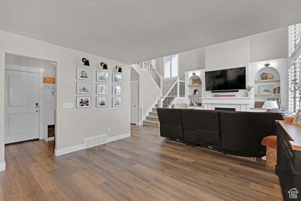 Living area with a fireplace, dark wood-type flooring, baseboards, stairway, and built in shelves