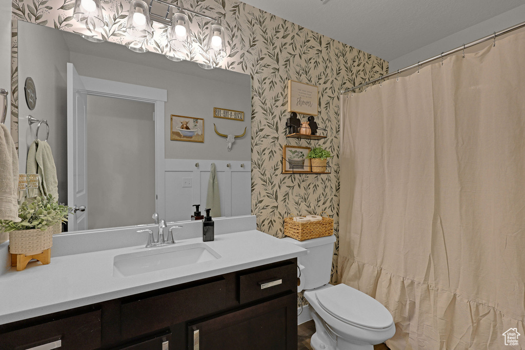 Bathroom featuring wallpapered walls, vanity, toilet, and a shower with curtain
