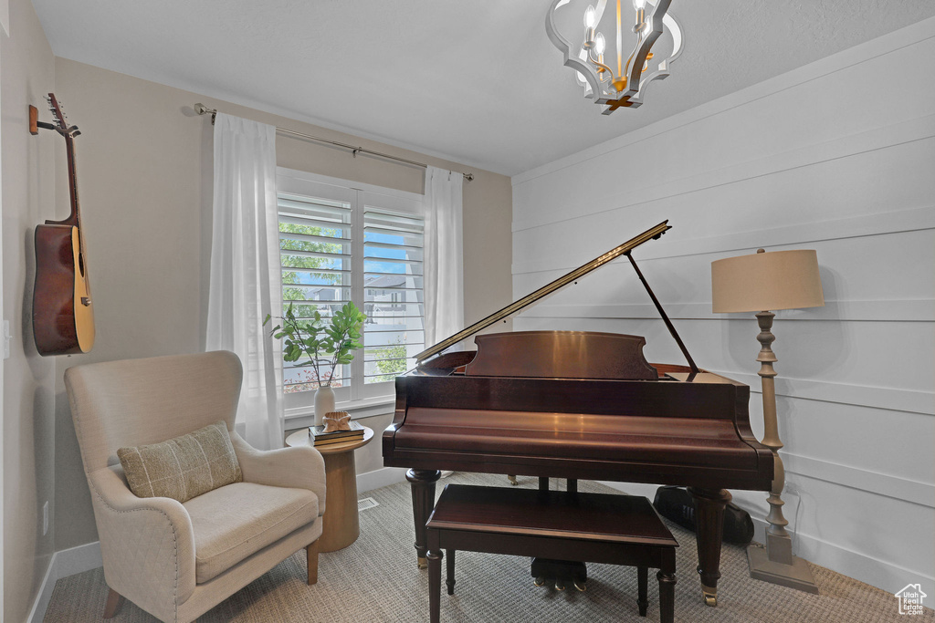 Living area with a chandelier, baseboards, and carpet flooring