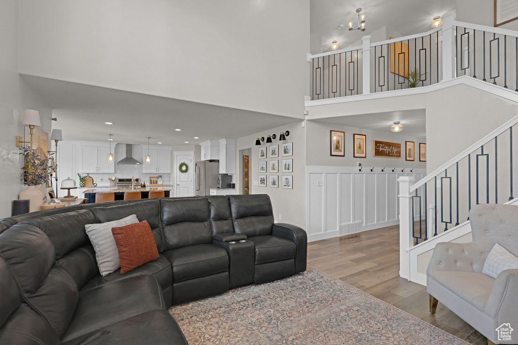 Living area with wood finished floors, stairs, a towering ceiling, and recessed lighting