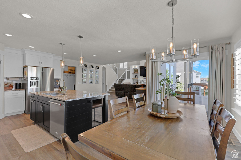Dining area with stairway, recessed lighting, light wood finished floors, and a textured ceiling