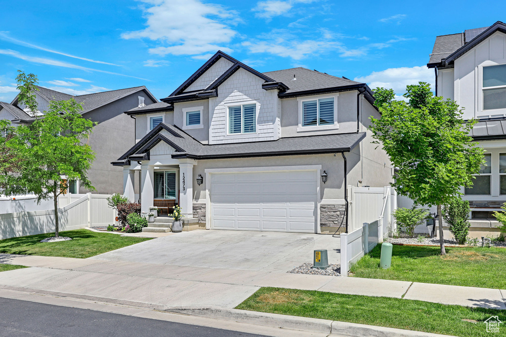 View of front of property featuring a garage, driveway, stucco siding, and stone siding