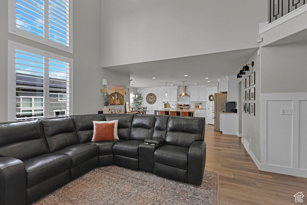 Living room featuring wood finished floors, a towering ceiling, and recessed lighting