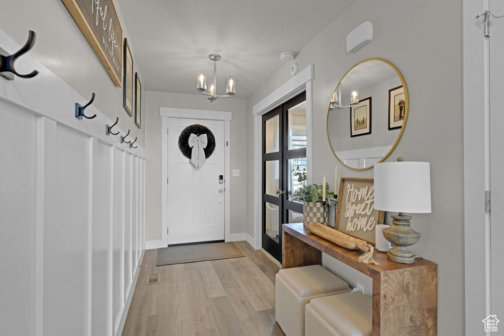 Foyer featuring a chandelier, light wood-style flooring, and baseboards