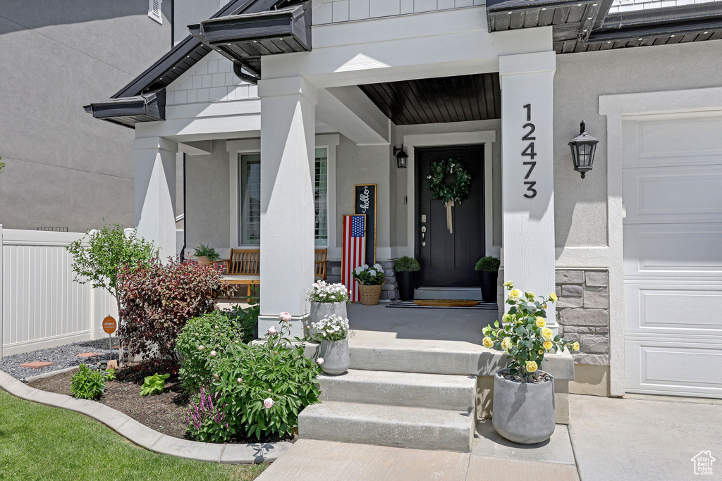Property entrance featuring a porch, stucco siding, and a garage