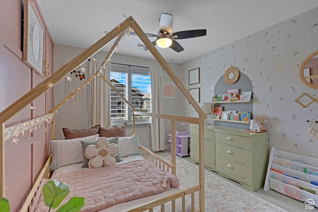 Bedroom with wallpapered walls, carpet floors, and a ceiling fan