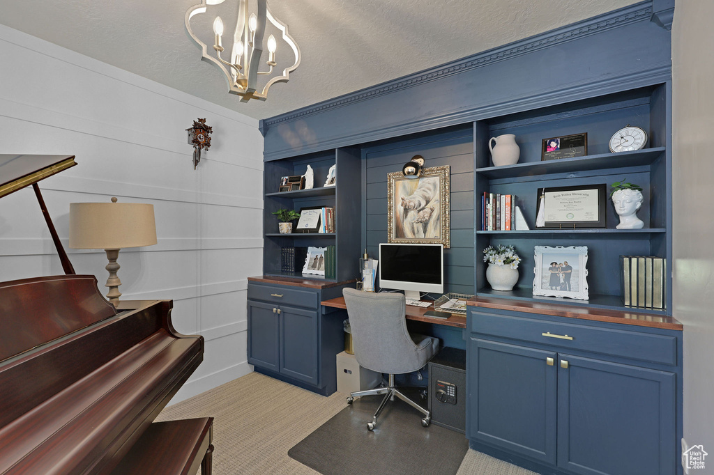 Office area featuring a chandelier, light carpet, built in shelves, and a textured ceiling