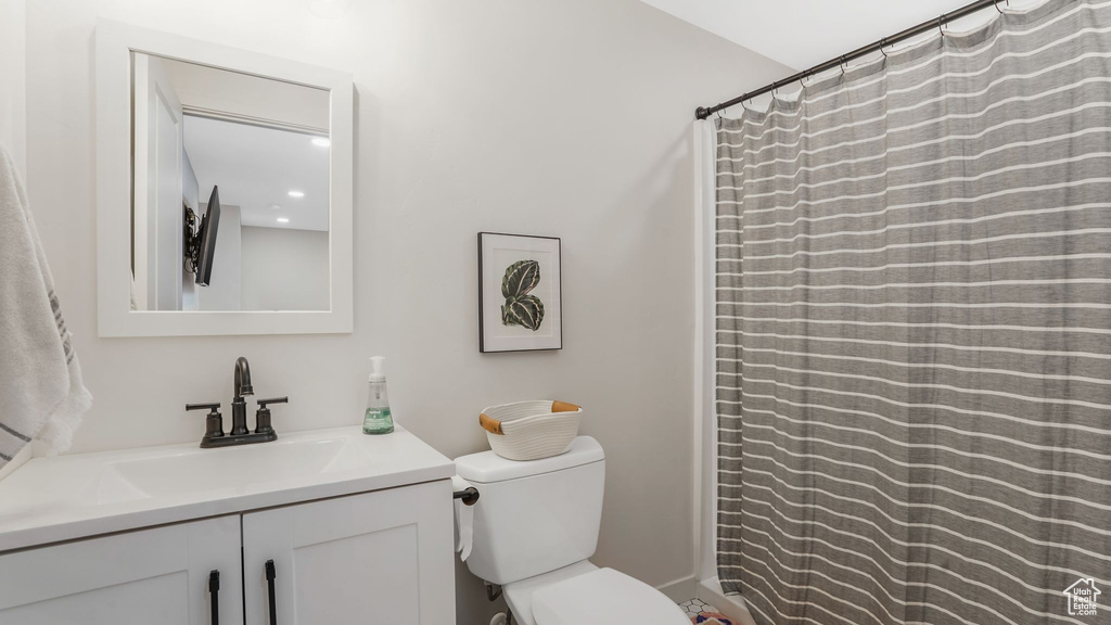 Bathroom with toilet, vanity, and curtained shower