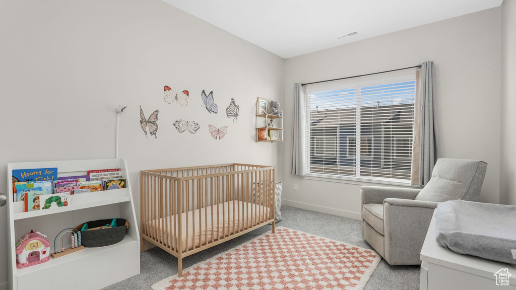 Carpeted bedroom with a crib and baseboards
