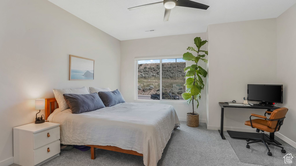 Bedroom with an office area, light colored carpet, baseboards, and ceiling fan