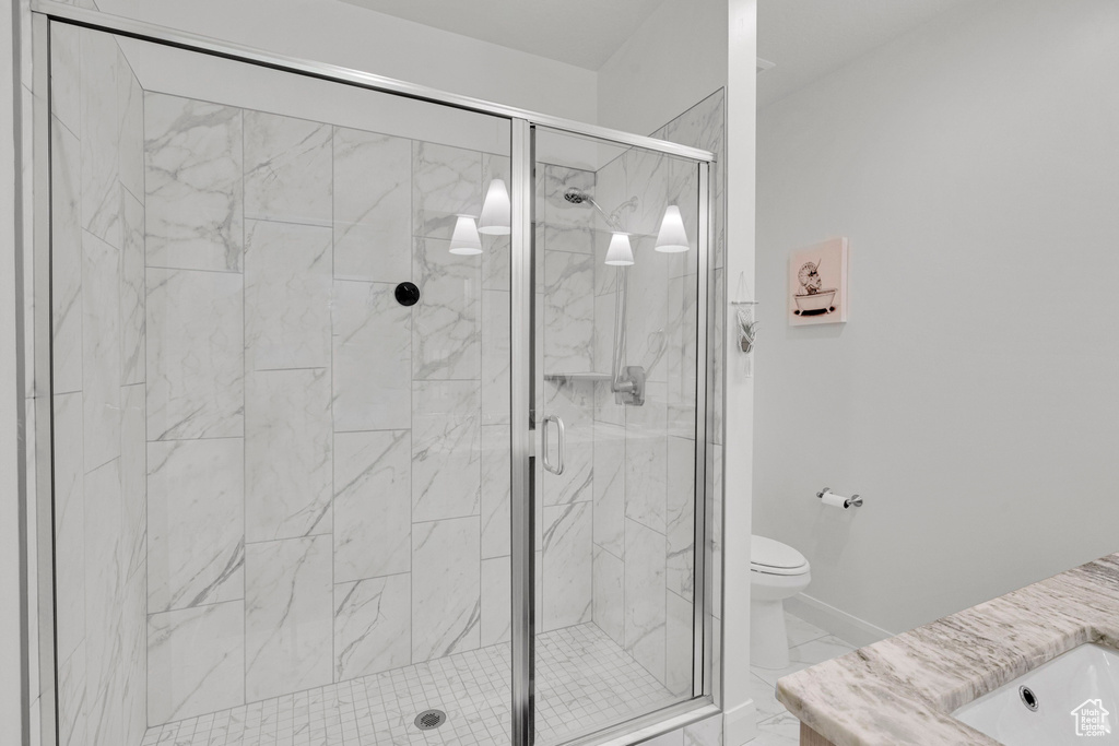 Full bath featuring a shower stall, toilet, marble look tile flooring, and vanity