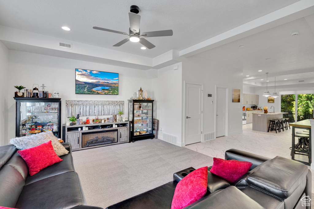 Living room with a ceiling fan, recessed lighting, baseboards, and a raised ceiling