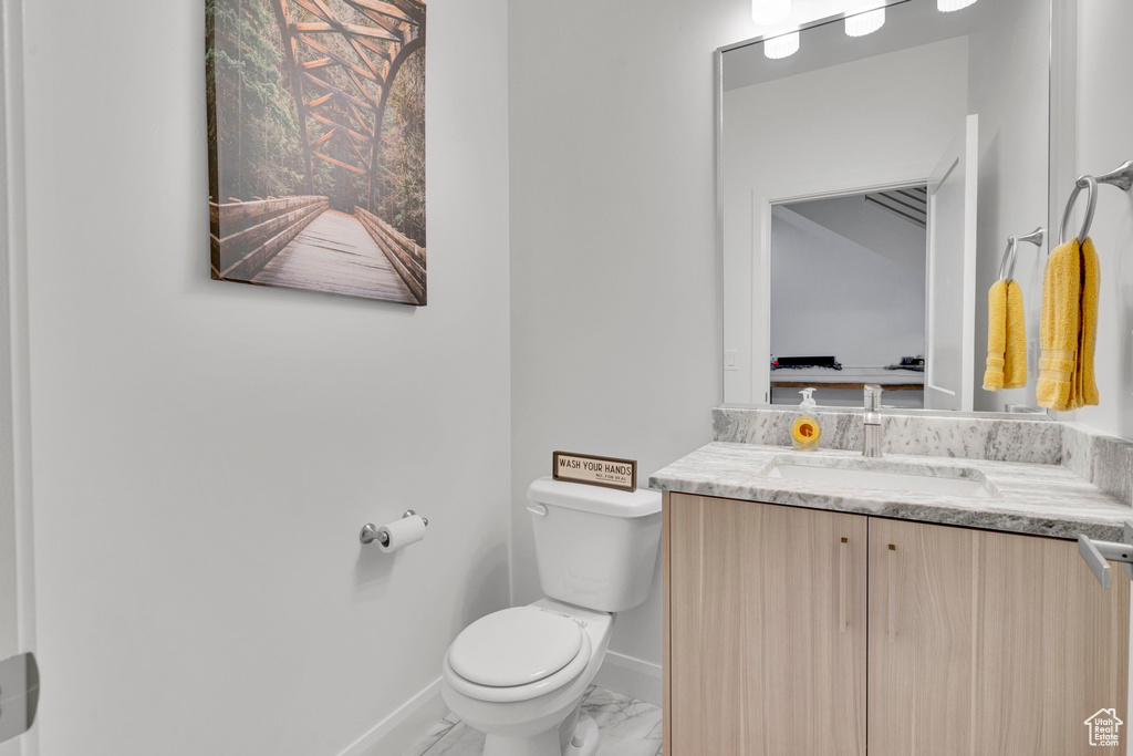 Bathroom with toilet, baseboards, marble finish flooring, and vanity