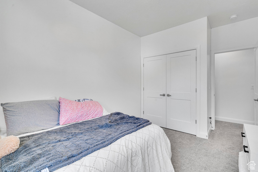 Carpeted bedroom with a closet and baseboards