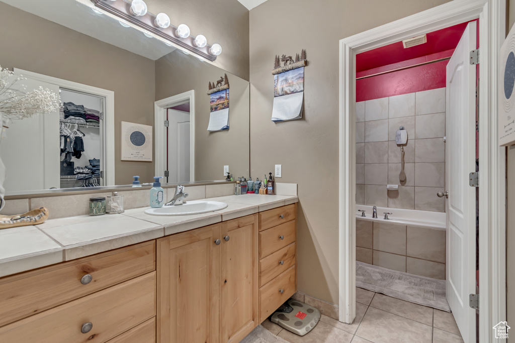 Bathroom featuring tile patterned flooring, vanity, and tiled shower / bath