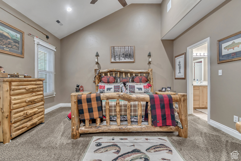 Carpeted bedroom featuring vaulted ceiling, connected bathroom, and baseboards