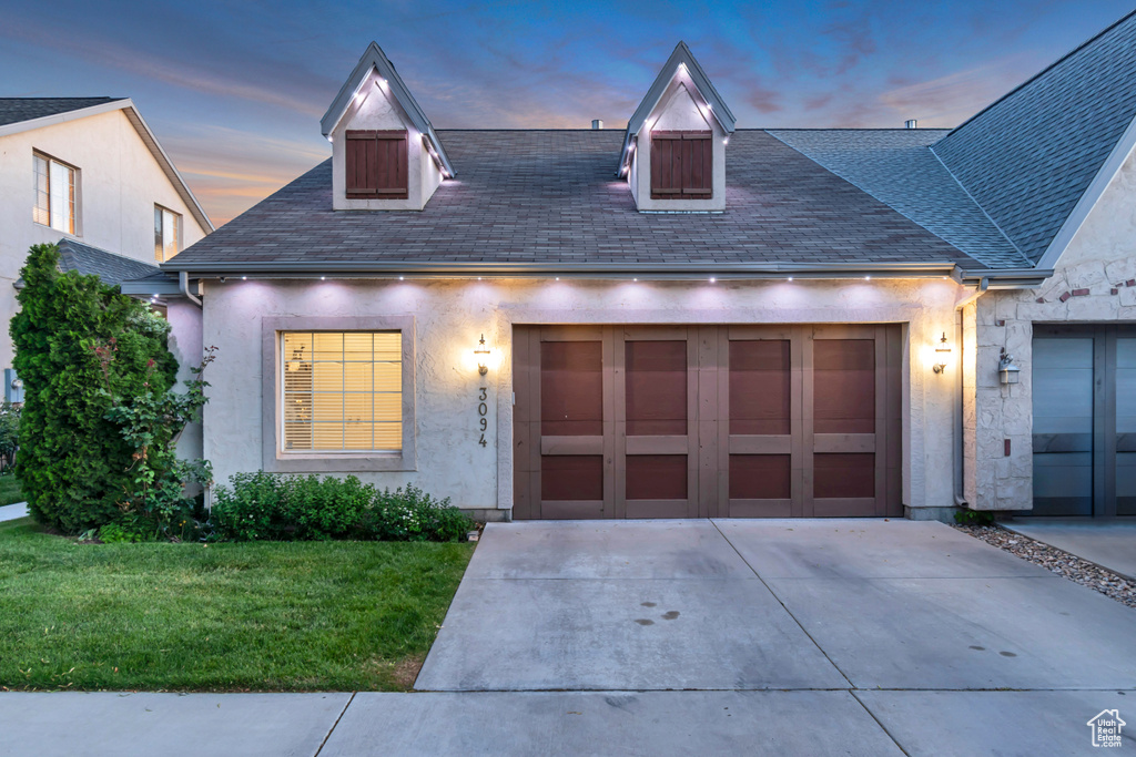View of front of property featuring driveway, a front yard, roof with shingles, an attached garage, and stucco siding
