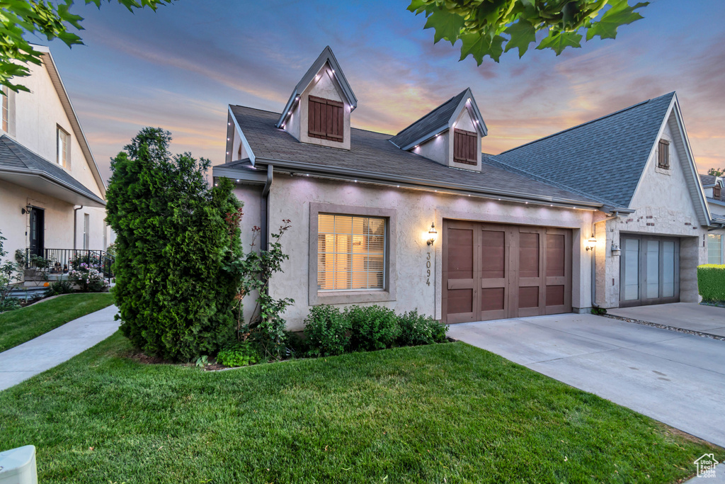 View of front of home with concrete driveway, an attached garage, a front yard, and stucco siding