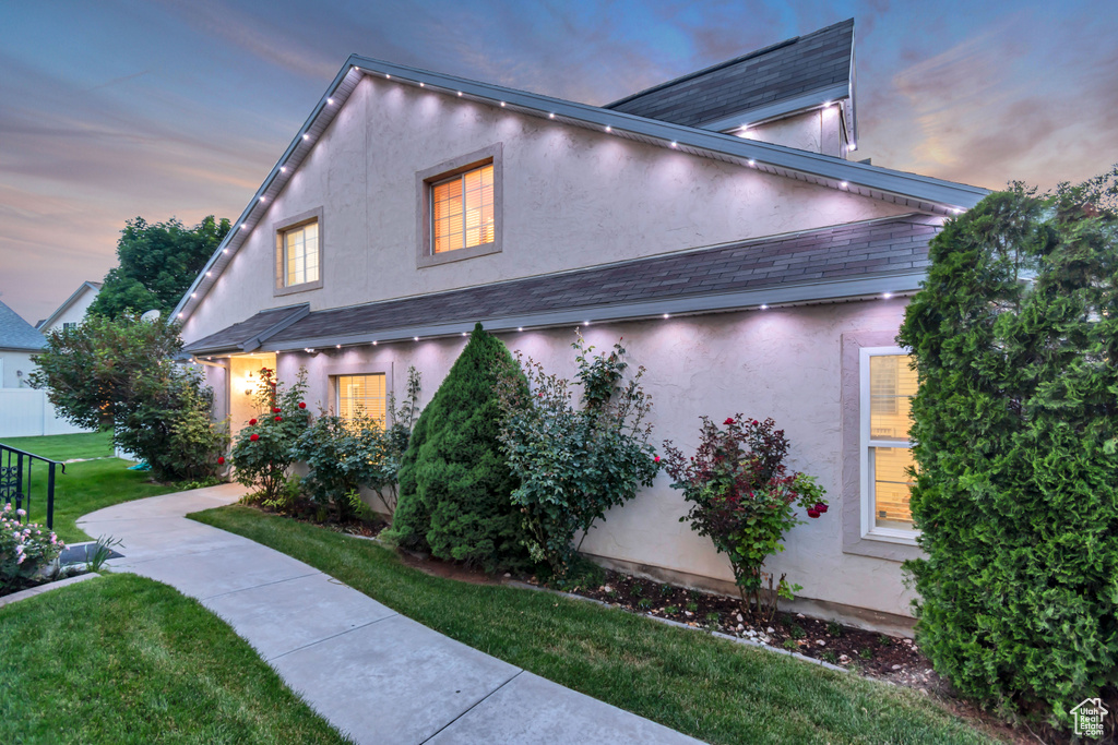 View of property exterior with stucco siding and a lawn