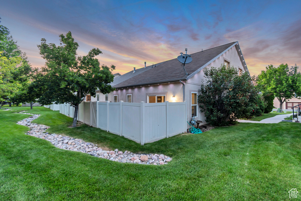 Back of property at dusk featuring a shingled roof and stucco siding