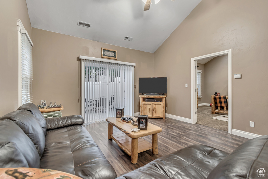 Living room featuring wood finished floors, vaulted ceiling, ceiling fan, and baseboards