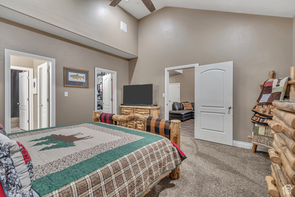 Bedroom featuring carpet flooring, high vaulted ceiling, a walk in closet, baseboards, and ensuite bathroom