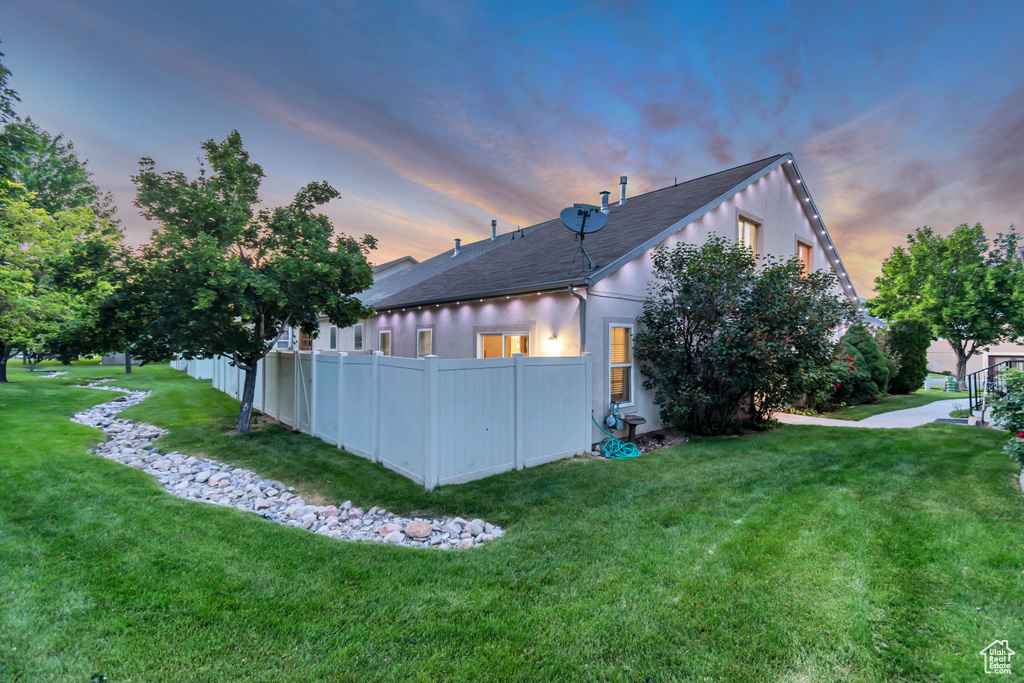 Back of house at dusk featuring stucco siding and a shingled roof