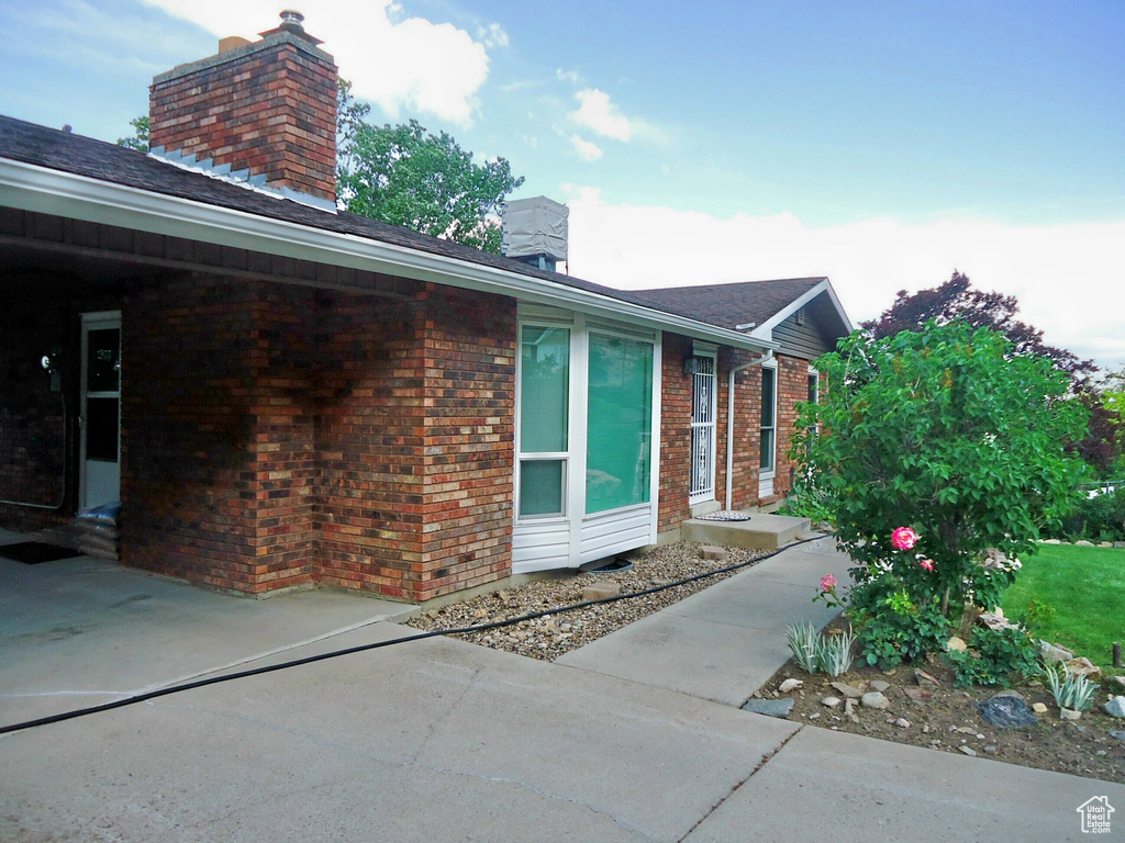 View of side of property featuring a chimney and brick siding