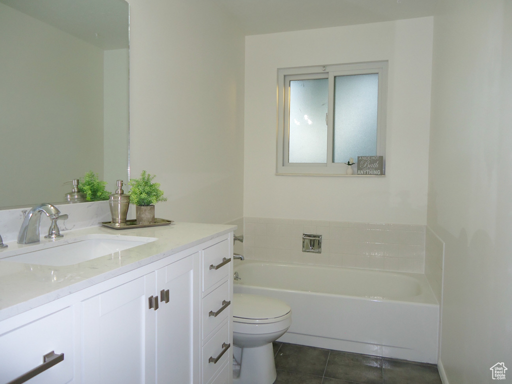 Bathroom featuring tile patterned flooring, a garden tub, vanity, and toilet