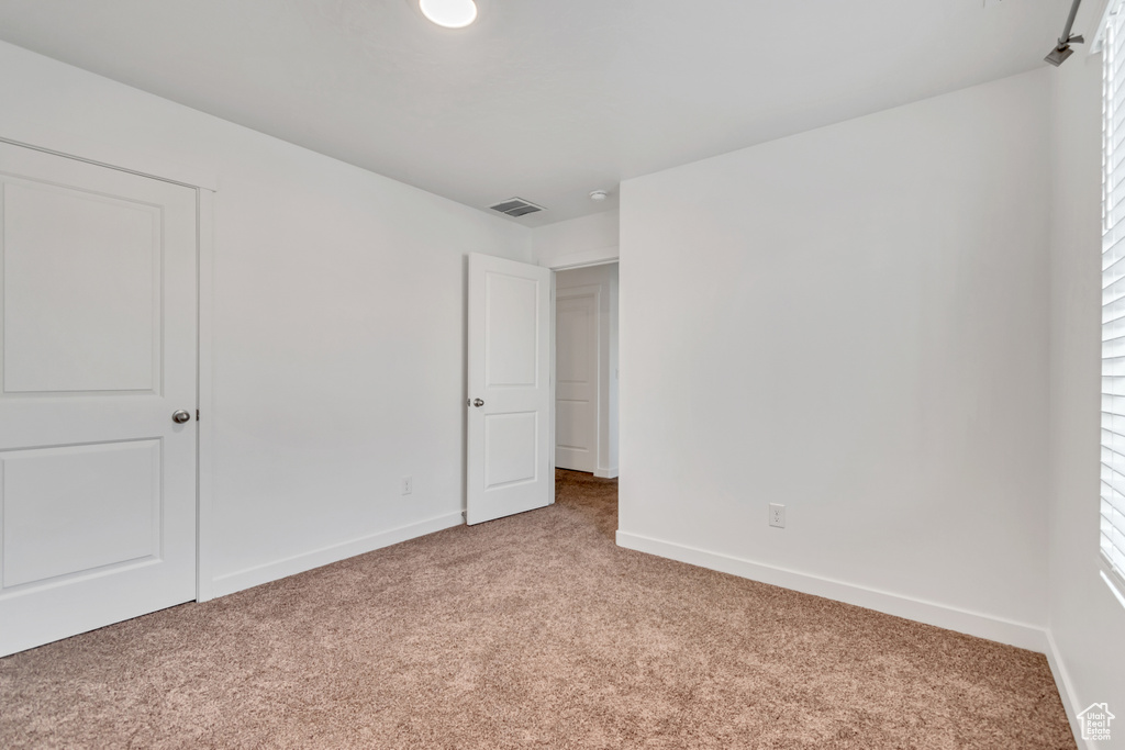 Unfurnished bedroom featuring light colored carpet, baseboards, and multiple windows