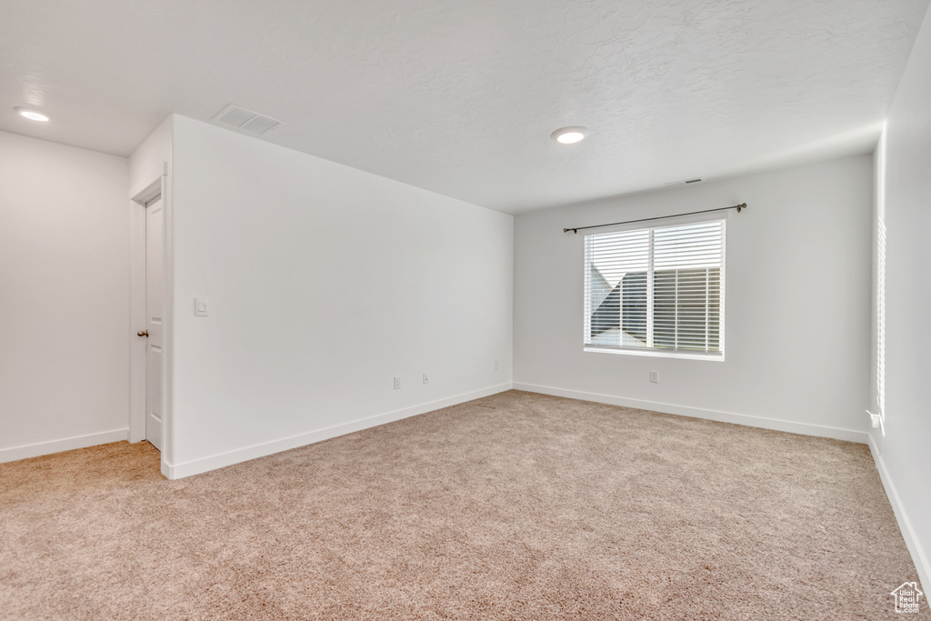 Empty room with light colored carpet, baseboards, and recessed lighting