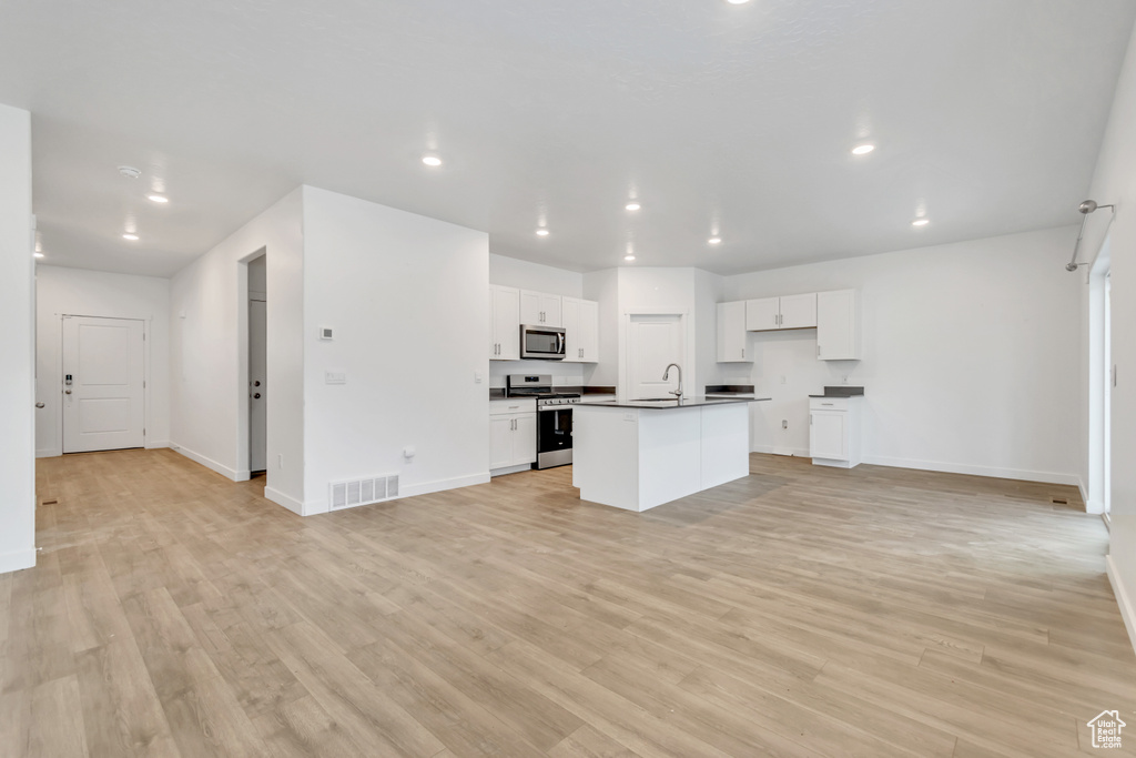 Kitchen with appliances with stainless steel finishes, dark countertops, open floor plan, baseboards, and recessed lighting