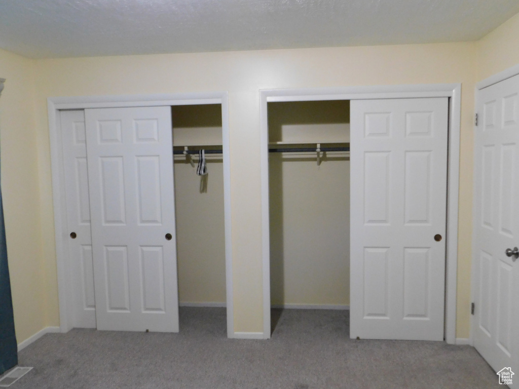 Unfurnished bedroom featuring multiple closets, carpet, and baseboards