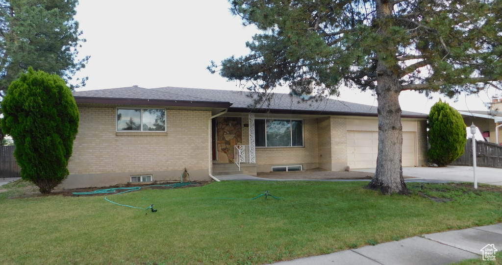 Single story home with brick siding, an attached garage, driveway, and a front lawn