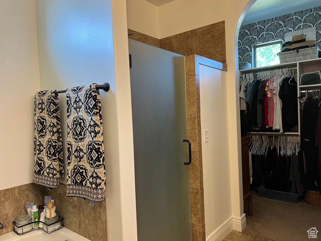 Full bath featuring a shower stall, a walk in closet, and a garden tub