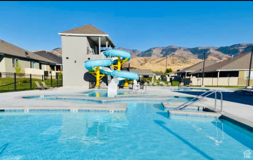 Community pool featuring a mountain view and a water slide