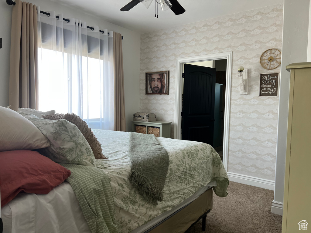 Carpeted bedroom featuring wallpapered walls, baseboards, and ceiling fan